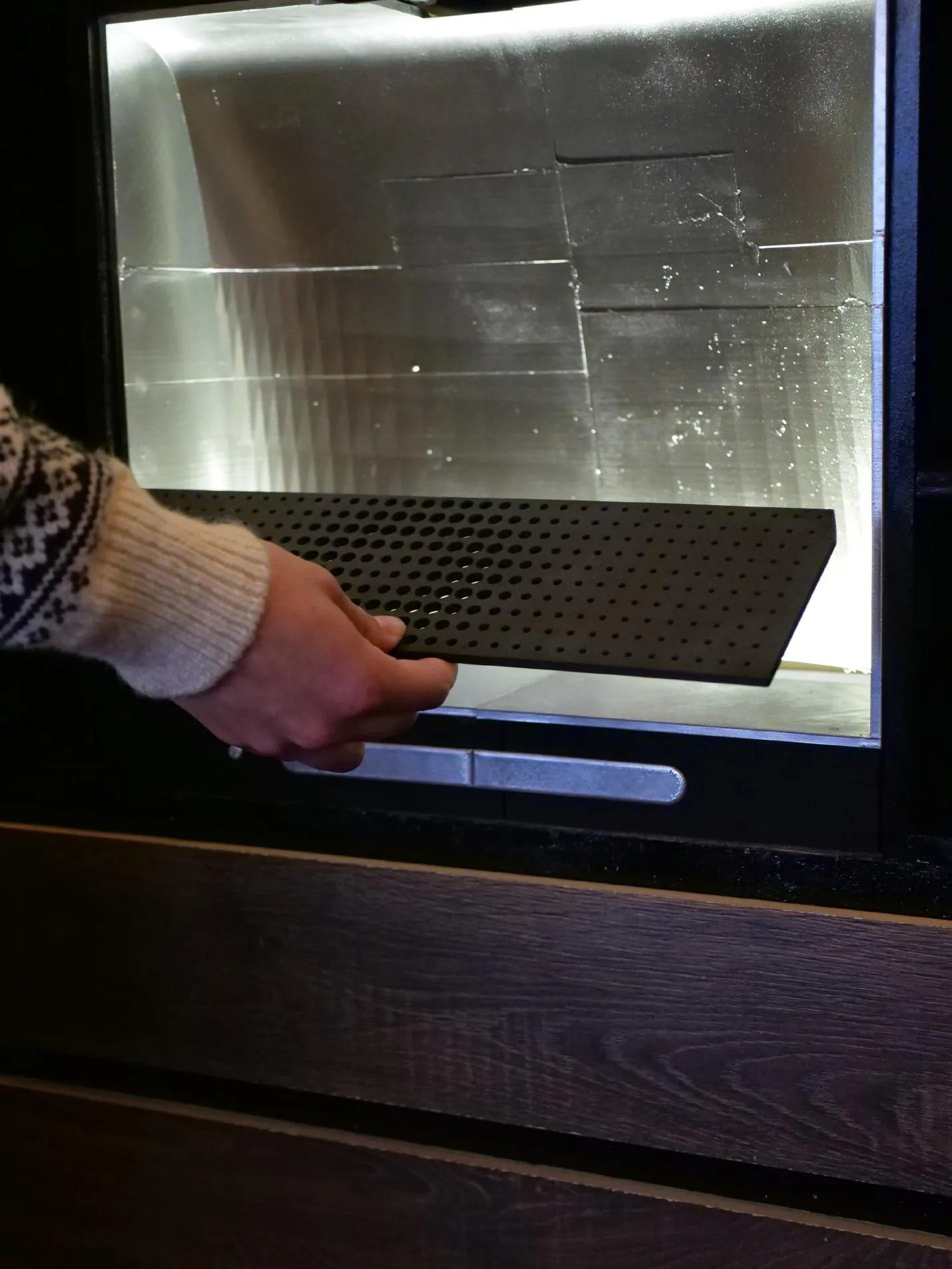 A hand opening the lit glass door of the prototype