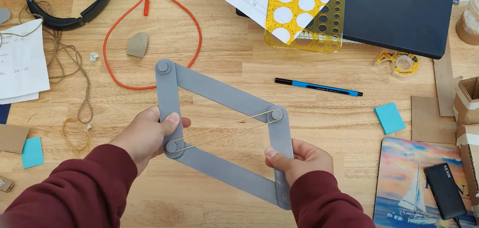 Hands testing a cardboard parallelogram arm prototype