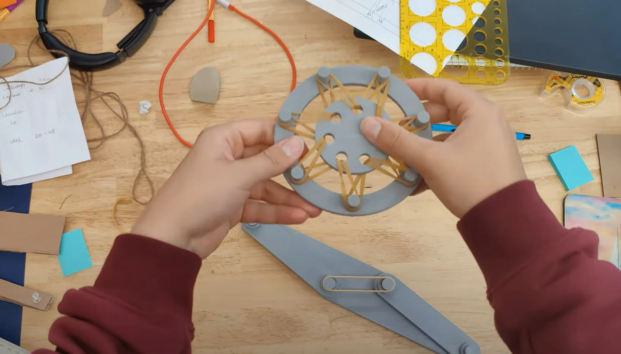 Hands holding a cardboard dual-ring vibration isolator prototype