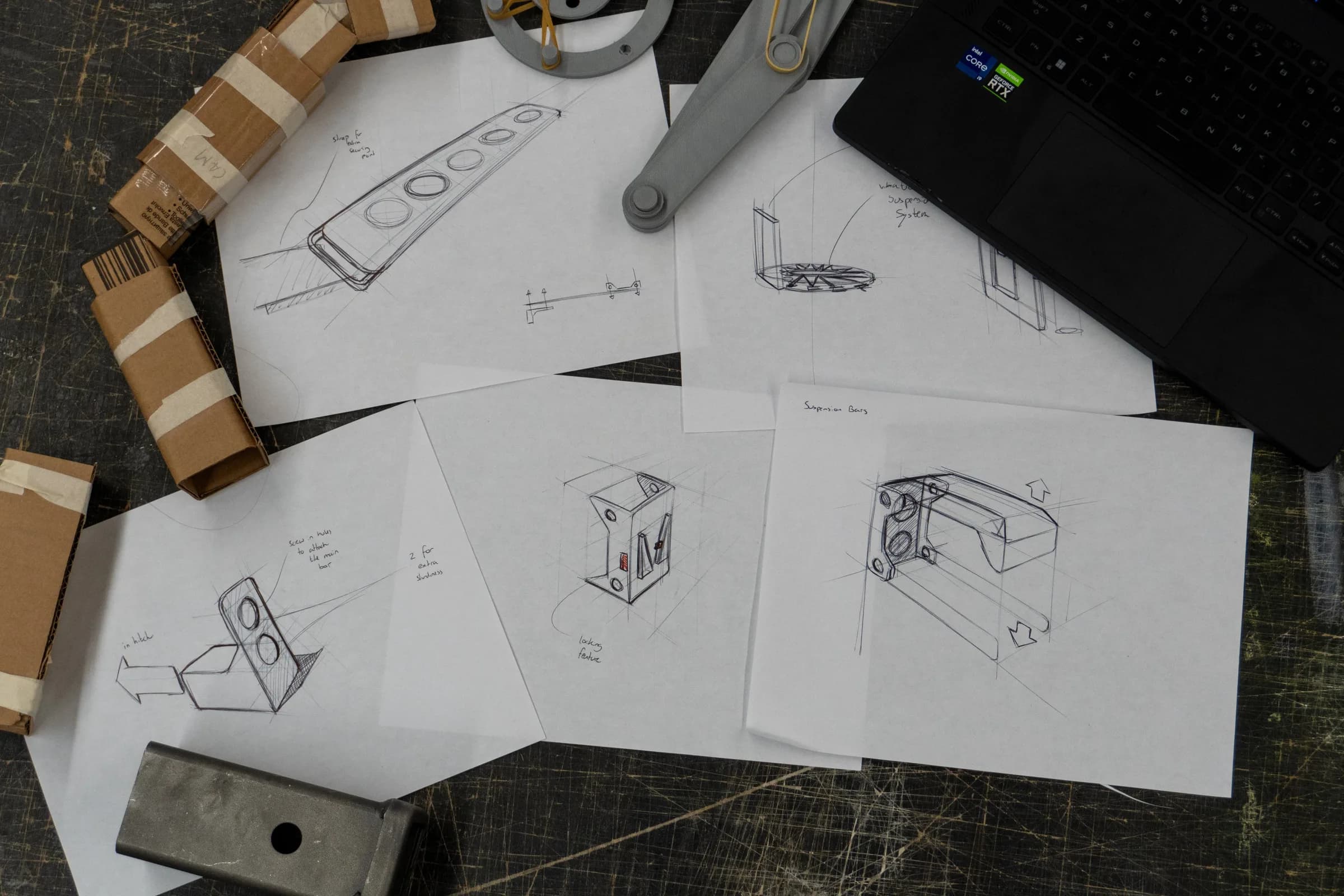 Pencil sketches of hitch brackets and arm concepts on a desk